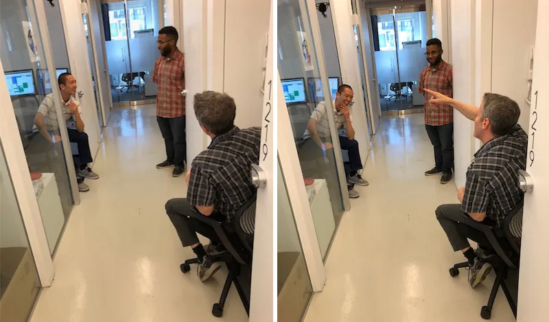 Three men in an office talking across a hallway